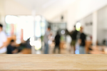 Empty wooden table with blurred businesspeople in meeting room. Copy space for display of product.