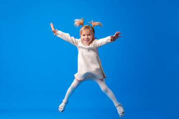 Portrait of little girl jumping on blue background