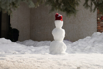 City snowman made  during January thaw with a house wall  background