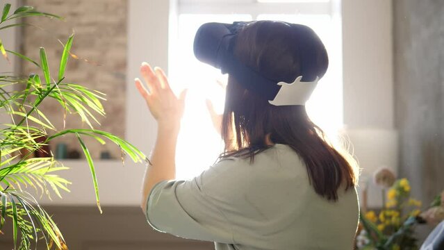 Woman plays with virtual reality glasses on a sunny day. Woman touching something with modern 3d vr glasses indoors.