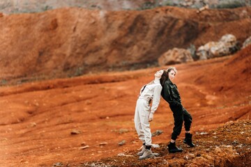 Girls in a post-apocalyptic place, a quarry with red earth and stones in work clothes