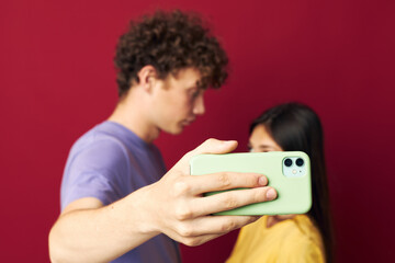 young man and girl in colorful T-shirts with a phone red background