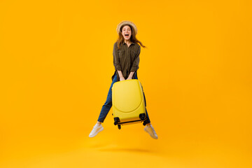 Joyful Tourist Woman Jumping Holding Suitcase Over Yellow Background