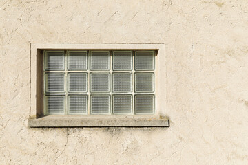 old  brick glass window with in the beige painted wall, space for text, no person