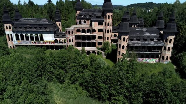 Lapalice castle surrounded by dense forest, aerial fly away from tower to far distance