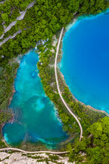 Plitvice, Croatia - Wooden walkway in Plitvice Lakes National Park on a bright summer day with crystal clear turquoise water, small waterfalls and green summer foliage