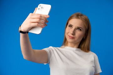 Happy woman taking selfie against studio color background