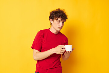 Young curly-haired man posing with a white mug and in the hands of a drink Lifestyle unaltered