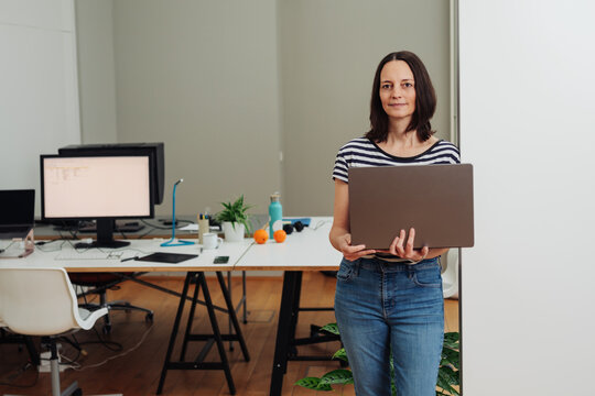 Businesswoman standing in her office holding a laptop computer