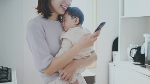 赤ちゃんを抱っこしながらスマートフォン操作をする女性