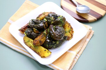 Baingan masala. Indian Potato and aubergine curry. Homemade Indian spicy eggplant and potato curry served in a white plate. Copy space.