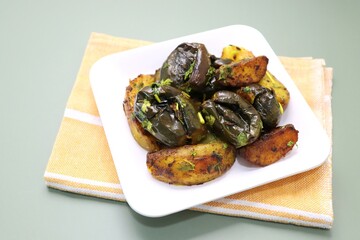 Baingan masala. Indian Potato and aubergine curry. Homemade Indian spicy eggplant and potato curry served in a white plate. Copy space.
