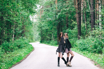 Fototapeta premium Two girls, blonde and brunette on the road in the summer forest