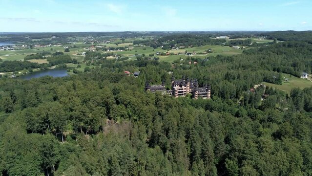 Castle of Lapalice surrounded by dense forest and small villages, high altitude drone shot