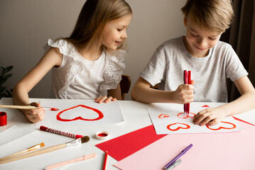 Kids painting red valetine heart card on table at home