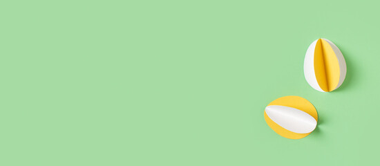 Yellow paper crafting eggs on green background, easter and spring concept