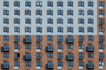 Fragment of a wall of a multi-storey white-brown building with windows and balconies