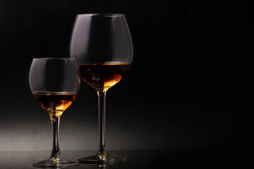 Glass glasses on a thin stem on a black background with wine.