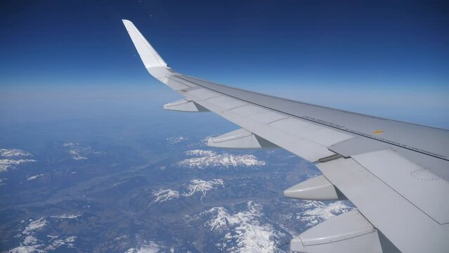 View from passenger cabin window of plane wing over Austrian Alps. High quality 4k footage