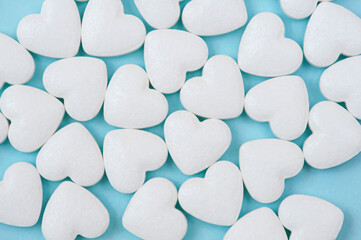 White heart shaped pills close-up on a blue background. Cardio disease treatment concept.