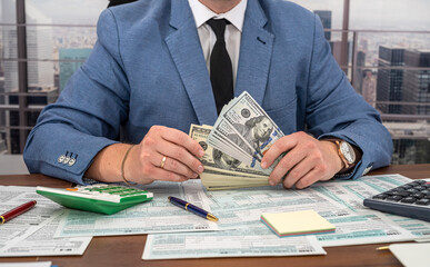 a man in office clothes works on tax forms of the United States and makes calculations for work
