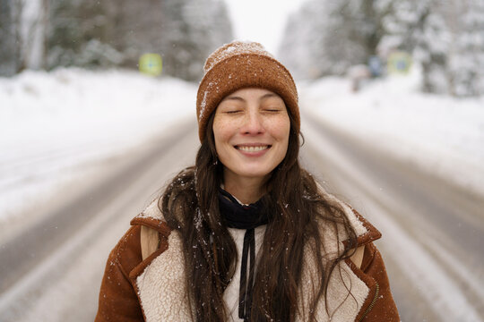 Enjoy winter outdoors. Portrait of young hipster girl happy laughing during walk in snowy pine forest, park or woods outside city. Joyful asian woman in warm hat and trendy coat enjoy frost and snow