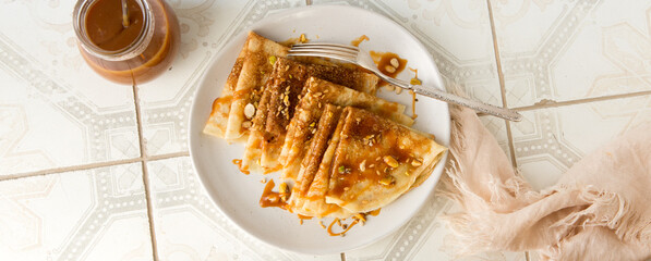 a plate of thin pancakes with salted caramel sauce on a light table