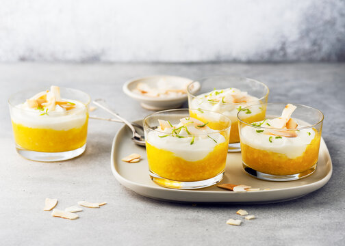 Vegetarian fruit cream dessert with coconut milk curd and mango puree in glass jars. Homemade healthy clean food concept. Copy space.