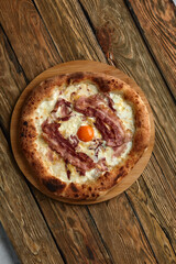 Carbonara pizza with bacon and egg on wooden background