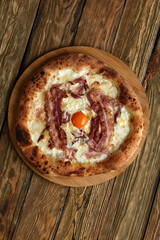 Carbonara pizza with bacon and egg on wooden background