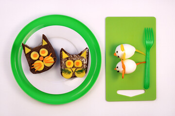 Fun food for kids. Funny cat sandwiches made from black rye bread and cheese and egg mouse on white background.