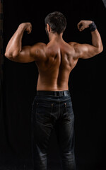 Fototapeta na wymiar muscular man. athlete posing in a black T-shirt and jeans. studio portrait
