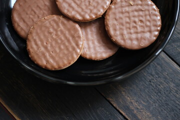 Chocolate flavored cookies Served in a black plate on a wooden table.
