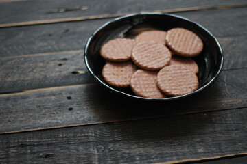 Chocolate flavored cookies Served in a black plate on a wooden table.