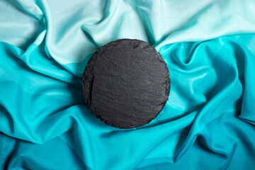 round black stone tile on silky blue gradient  background. Product photography mockup