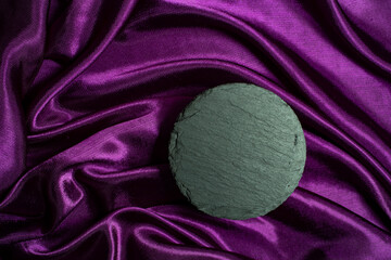 round black stone tile, on purple satin background, product photography backdrop