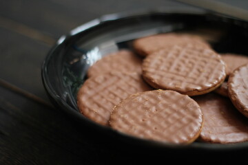 Chocolate flavored cookies Served in a black plate on a wooden table.