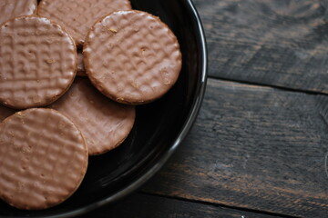 Chocolate flavored cookies Served in a black plate on a wooden table.