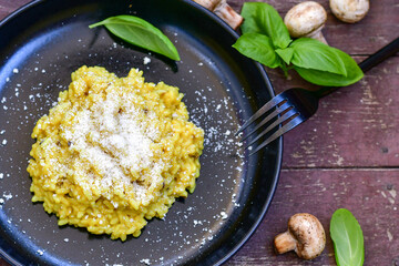  Italian  creamy Risotto Milanese  with Parmesan cheese and fresh basil on rustic background