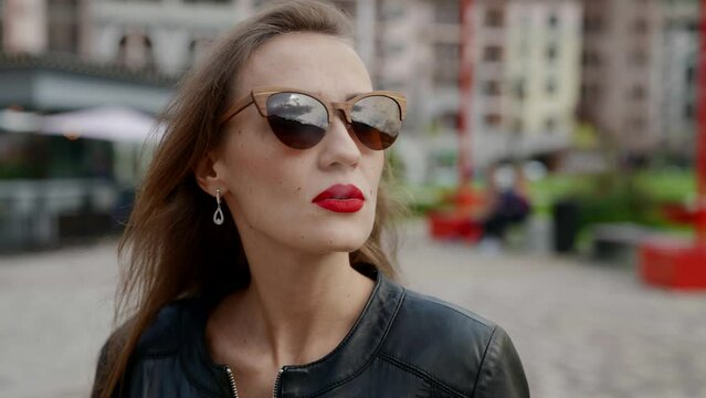 portrait of a smoking woman with bright lipstick and sunglasses. the camera is moving around. close-up