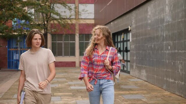 Teenager girl going home after classes in school with other teens who walking in background. . High quality 4k footage