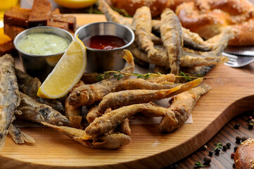 fried small fish on a board with sauce
