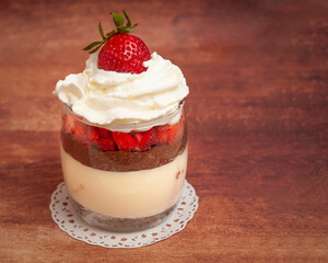 Glass with chocolate pudding, duo color chocolate flakes, whipped cream, strawberries and biscuits