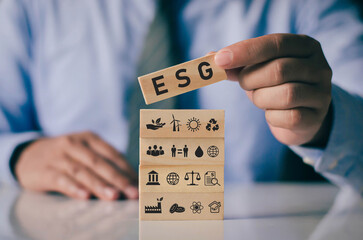 Businessman with wooden block on hand ESG icon concept for environmental, social and governance in...