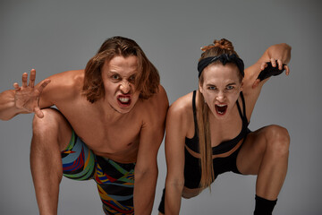 Beautiful young acrobats or gymnasts on gray background. Professional ballet couple dancing,...