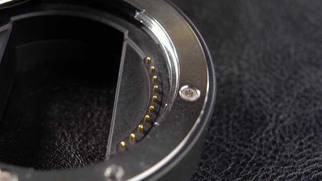 Lens extension bayonet with metal contacts. Macro. Rotation. Mount adapter. On black surface