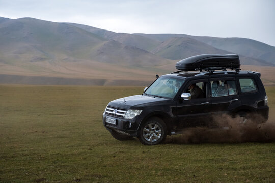 Offroad suv Mitsubishi pajero running on mountain valley throwing away dirt and soil under wheels. Summer road trip.
