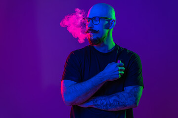 adult man is using electronic cigarette, exhaling vapor in studio. color filters. Vaping concept