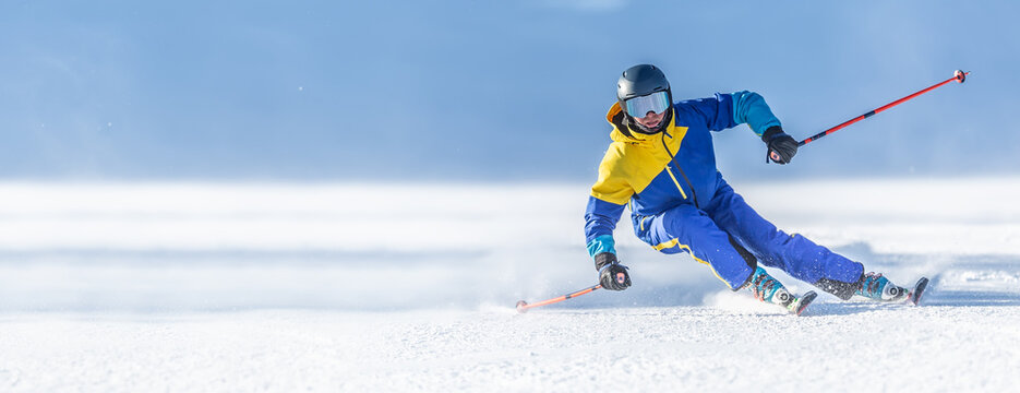 A young aggressive skier on an alpine slope demonstrates an extreme carving skiing style.