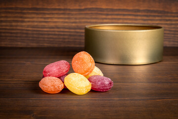 Colored candies stacked on a wooden texture and a metal box in the background
